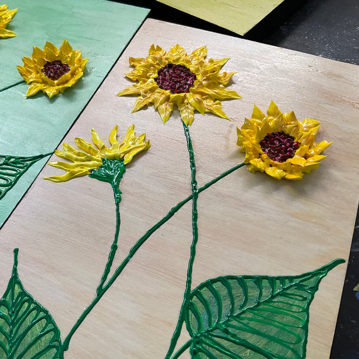 yellow sunflowers with green leaves on brown background textured floral painting by Bala Thiagarajan, hand-piped acrylic on wood panel with iridescent sculptural detail